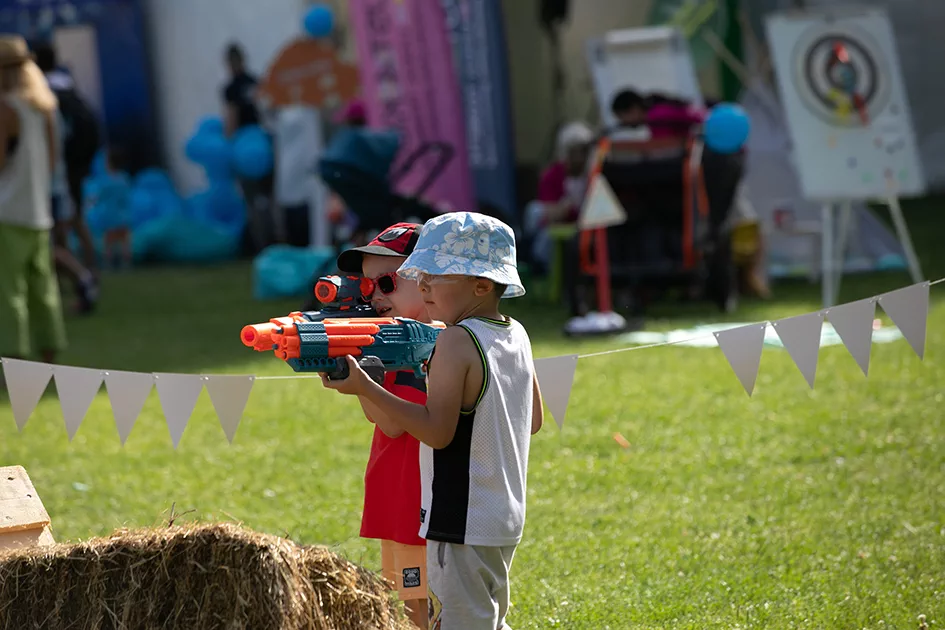 Copii participând la activitatea Nerf Arena pe peluza festivalului.